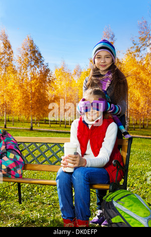 Two happy school age happy smiling girls playing guessing who am I covering eyes with palms, holding coffee Stock Photo