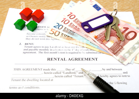 Rental agreement with keys, deposit money, pen and toy wooden houses Stock Photo
