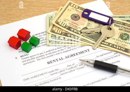 Rental agreement with keys, deposit money, pen and toy wooden houses Stock Photo