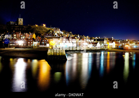 The pretty North Yorkshire, UK harbour town of Whitby, photographed at night with lights reflected in the sea in the harbour. Stock Photo