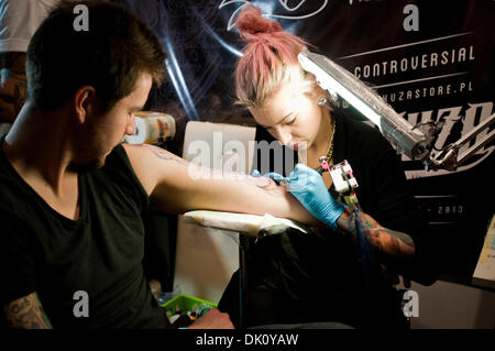 Warsaw, Poland. 1st December 2013. Female tattoo artists make a new tatoo on her client's arm during the second day of tattoo, body painting and pierceing show - 1st Warsaw Tattoo Convention 2013 in Pepsi Arena in Warsaw, Poland Credit:  kpzfoto/Alamy Live News Stock Photo