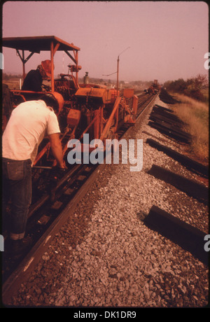 SOUTHERN RAILWAY RIGHT-OF-WAY WORK CREW, WITH A MACHINE THAT DRIVES SPIKES INTO THE RAILROAD TIES TO HOLD THE NEW... 556883 Stock Photo