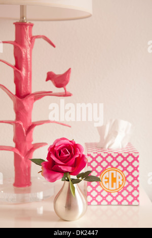 Pink lamp, rose and monogrammed tissue box on nightstand Stock Photo