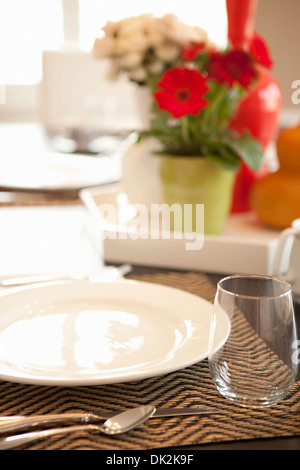 Close up of place setting on dining table with flower arrangement Stock Photo