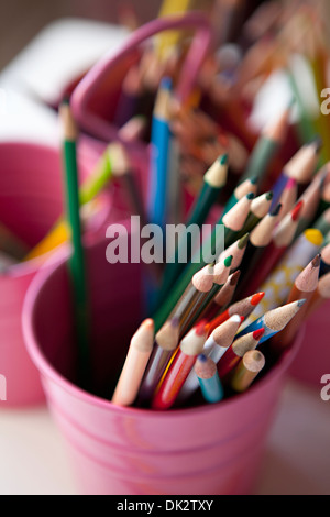 Close up high angle view of multicolor art colored pencils in pink bucket Stock Photo