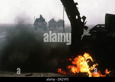 Armored personnel carriers of the 7th Brigade Royal Scots, 1st United Kingdom Armored Division, pass a burning Iraqi anti-tank vehicle while advancing east into Kuwait from southern Iraq during Operation Desert Storm February 28, 1991 in Kuwait. Stock Photo
