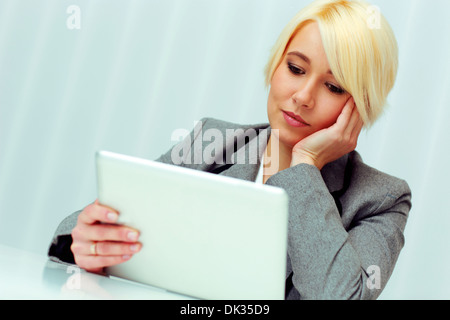 Thoughtful businesswoman holding tablet computer in office Stock Photo
