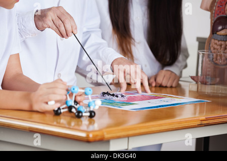 Male Teacher With Students Experimenting At Desk Stock Photo
