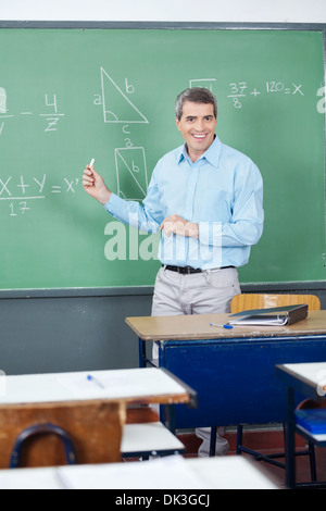 Male Teacher Teaching Mathematics On Board Stock Photo