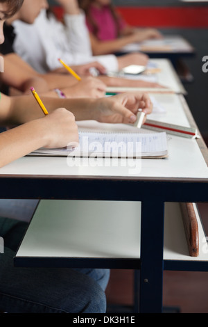 Schoolchildren Writing In A Row At Desk In Classroom Stock Photo