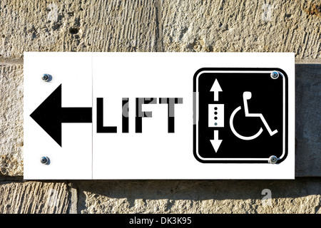 Sign with arrow showing direction to lift / elevator for wheelchair users and handicapped persons to access public building Stock Photo