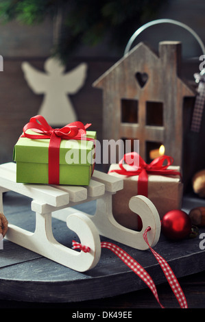 Sled toy with gift boxes and lantern on wooden background Stock Photo