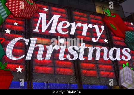 Close up Merry Christmas sign decoration in lights on shop building  front above entrance at night on Boots store in West End Oxford Street London UK Stock Photo