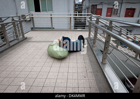 Chinese man have a nap on footbridge over Fuxing Road in Huangpu District, Shanghai, China Stock Photo