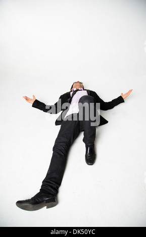 Professional young man laying on ground with arms outstretched Stock Photo