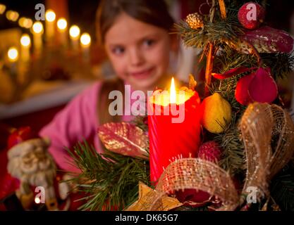 Frankfurt Oder, Germany. 28th Nov, 2013. ILLUSTRATION - An illustrated picture shows seven year old Amy from Boossen near Frankfurt Oder smiling behind a burning candle in an Advent arrangement in Frankfurt Oder, Germany, 28 November 2013. The Advent season with its light sand decorations prepares the mood for Christmas. Photo: Patrick Pleul/dpa/Alamy Live News Stock Photo