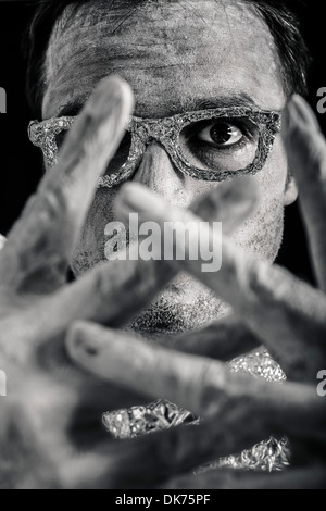 Closeup of scary mysterious man face through his hands. Stock Photo