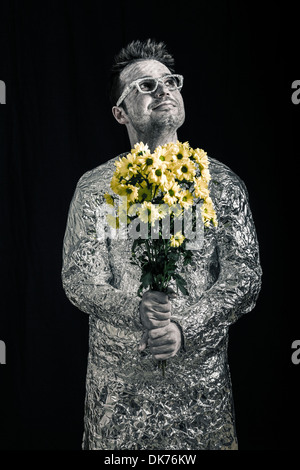 Portrait of happy spaceman holding flowers and looking up. Stock Photo