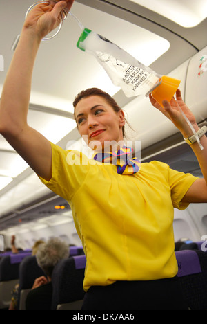 Air steward explains the safety procedures to passengers on a commercial airliner before departure, stewardess safety procedure Stock Photo