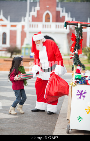 Santa Claus Giving Gift To Girl Stock Photo - Alamy