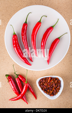 Fresh and dried red hot chili peppers on wooden background. Stock Photo