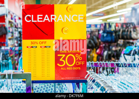 Sign indicates clearance sale discounts on clothing in retail