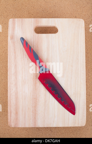 Big red knife on wooden chopping board. Stock Photo