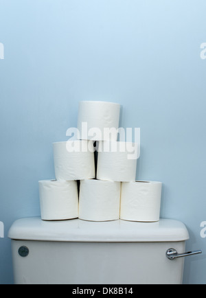 White toilet rolls stacked on top of toilet tank Stock Photo