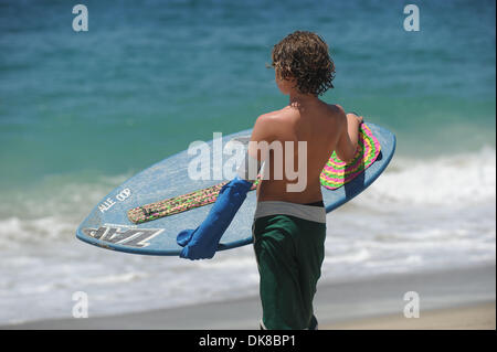 A young boy with a home made waterproof cast made out of a kitchen glove gets in the water after the Victoria Skimboards World Championship of Skimboarding 2011 at Aliso beach on July 17, 2011. Stock Photo