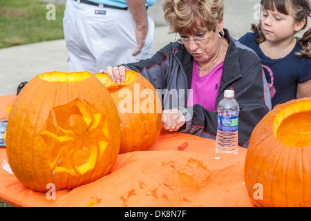 Young girl watches senior woman carving pumpkins for Halloween Stock Photo