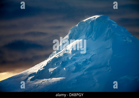 Antarctica, Setting sun lights windblown snow on mountain peaks along Neumayer Channel Stock Photo