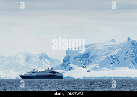 Antarctica, Cruise ship motoring past glacier-covered mountains on Anvers Island along Gerlache Strait Stock Photo