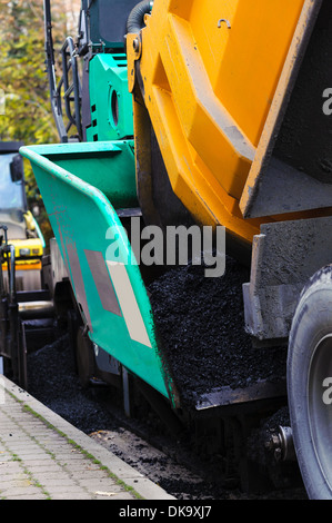 Truck dumping asphalt to running paving machine Stock Photo