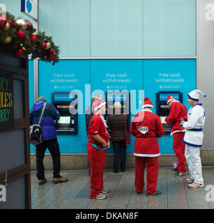 Charity Santa Dash in Liverpool runners break to get cash at Barclays hole in the wall cash machine Stock Photo