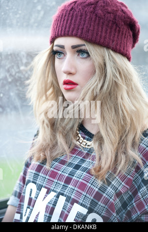 Teenage girl with long blonde hair standing outside at a bus stop. Stock Photo