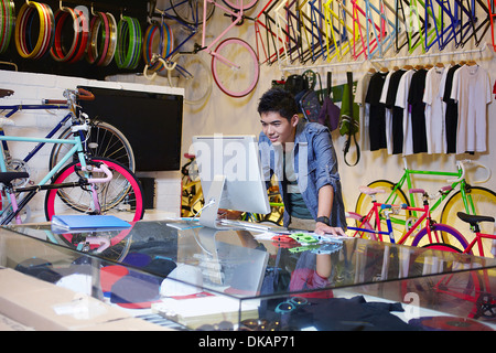 Young man in bike shop using computer Stock Photo