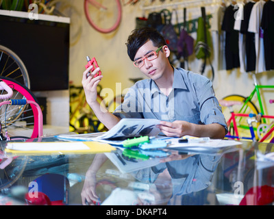 Young man examining bicycle part in bike shop Stock Photo