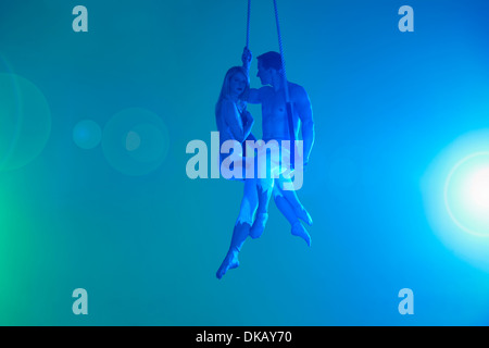 Couple sitting on trapeze Stock Photo