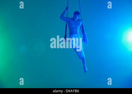 Man sitting on trapeze Stock Photo