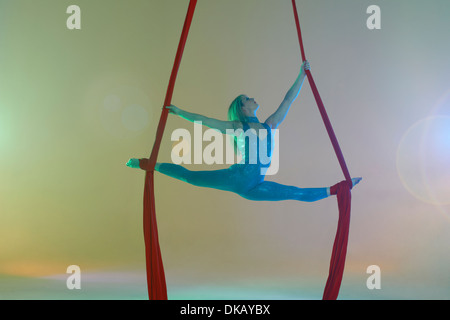 Aerial dancer doing the splits with red ribbon Stock Photo