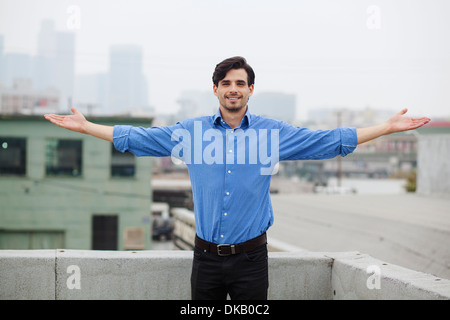 Confident young man with open arms on city rooftop Stock Photo