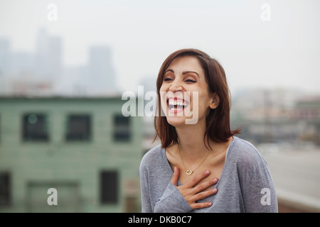 Woman laughing on city rooftop Stock Photo