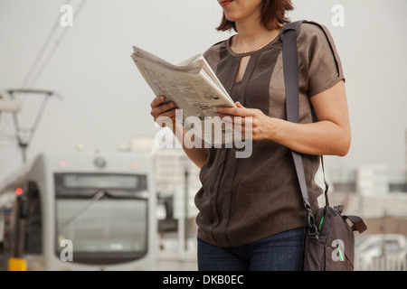 Commuter reading newspaper whilst waiting at station, Los Angeles, California, USA