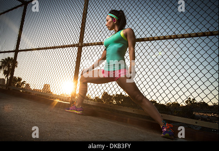 Female runner stretching on walkway Stock Photo