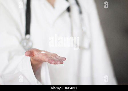 Close up studio shot of female doctor holding pill in hand Stock Photo