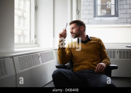 Casual businessman looking out of window Stock Photo