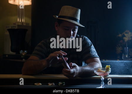 Mid adult man sitting at table shuffling cards Stock Photo