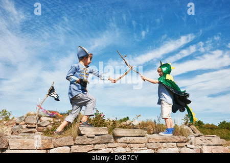 Two boys in fancy dress play fighting with sticks, Eggergrund, Sweden Stock Photo