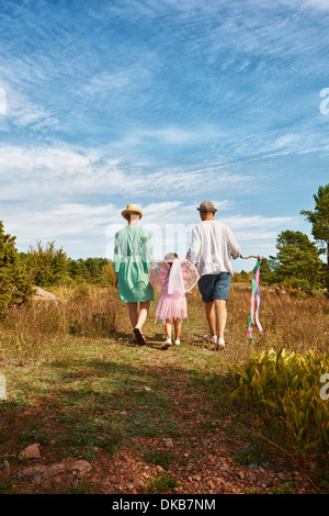 Family walking on grass, rear view, Eggergrund, Sweden Stock Photo