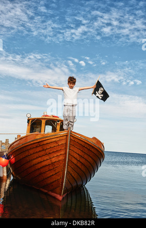 Portrait of boy on boat holding pirate flag, Eggergrund, Sweden Stock Photo